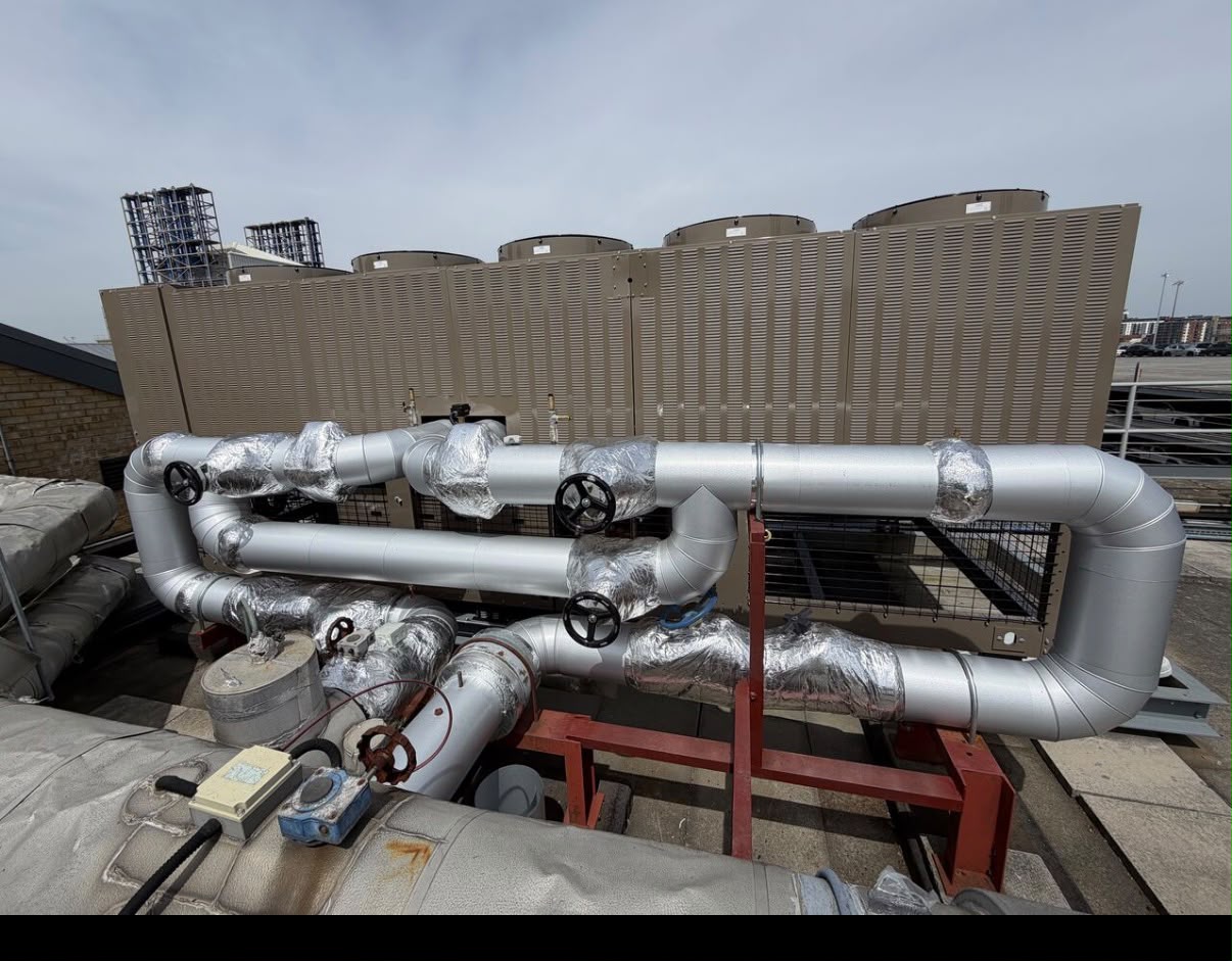 RAC insulation work showing metal-clad rooftop pipework and insulated valves beside cooling equipment